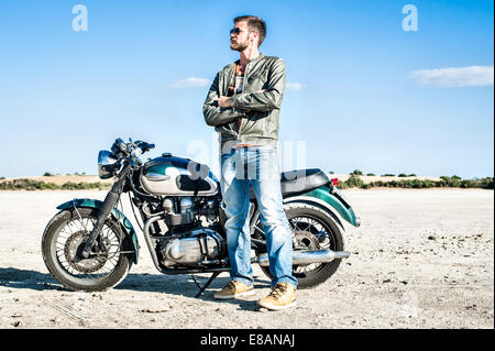 Ritratto di giovane maschio motociclista sulla pianura arida, Cagliari, Sardegna, Italia Foto Stock