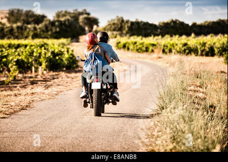 Vista posteriore della metà adulto giovane in sella del motociclo avvolgimento sulla strada rurale, Cagliari, Sardegna, Italia Foto Stock