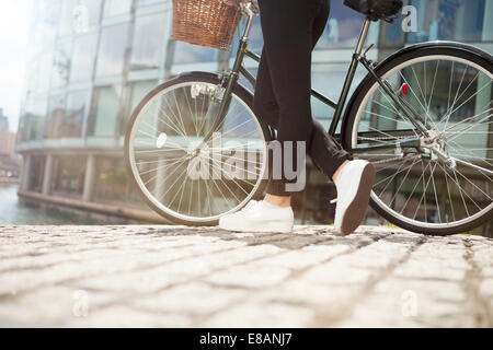 Donna spingendo in bici lungo il canale Foto Stock