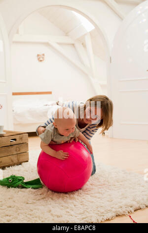 Coppia madre e figlia femmina sulla parte superiore della palla ginnica in salotto Foto Stock