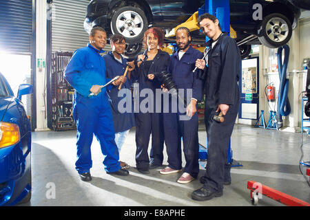 Ritratto di cinque studenti del college sotto auto in garage officina Foto Stock