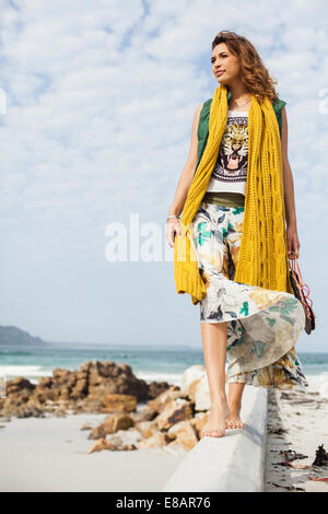 Giovane donna guardando dal blocco di cemento sulla spiaggia, Cape Town, Western Cape, Sud Africa Foto Stock