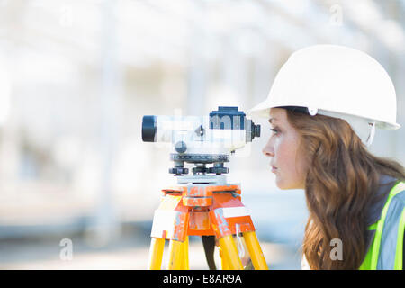 Geometra femmina guardando attraverso il livello sul sito in costruzione Foto Stock