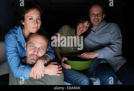 Due coppie mature a guardare la TV con snack bocce Foto Stock