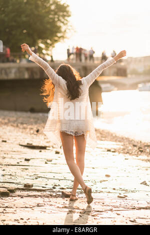 Giovane donna passeggiate lungo il fiume, braccia Foto Stock