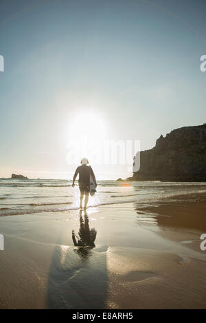 Senior Donna che cammina verso il mare con la tavola da surf, Camaret-sur-mer, Bretagna Francia Foto Stock