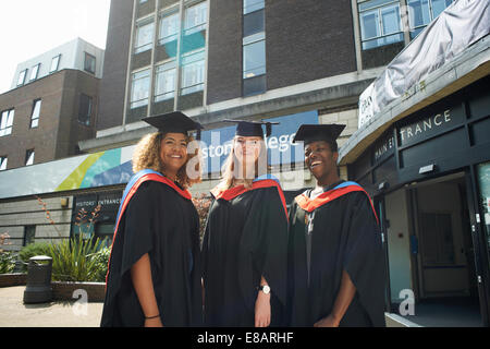 Ritratto di tre studenti del college in abiti di graduazione e tappi Foto Stock