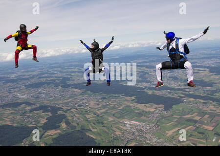Team di tre skydivers in sit fly posizione sopra Buttwil, Lucerna, Svizzera Foto Stock