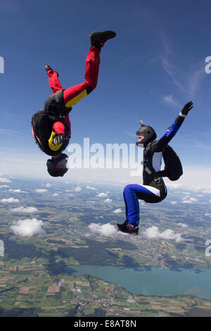 Team di due femmina skydivers in sit volare e a testa in giù su posizioni Buttwil, Lucerna, Svizzera Foto Stock