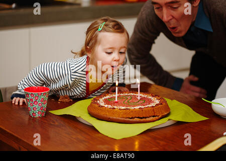 Giovane ragazza che spegne le candeline sulla torta del compleanno sulla torta Foto Stock
