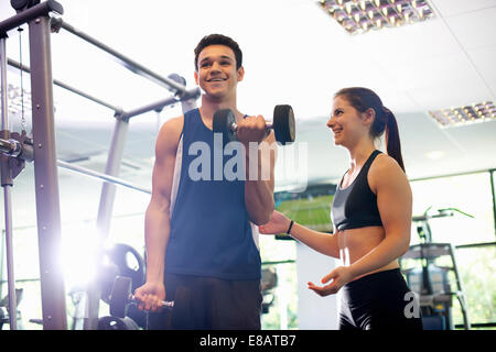 Personal trainer aiutando i giovani man mano di sollevamento pesi Foto Stock