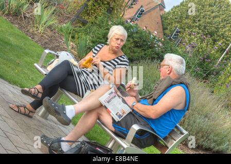 Due persone su una panchina nel parco di mangiare Foto Stock