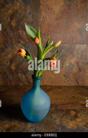 Tulipani arancio blu con bottiglia di vetro Foto Stock