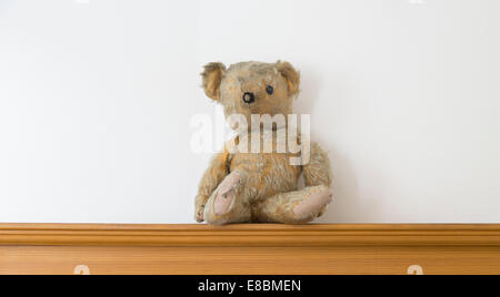 Threadbare uno Eyed orsacchiotto di peluche su uno scaffale di legno Foto Stock