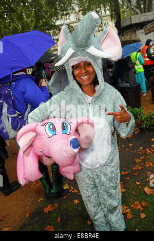 Londra, Regno Unito. Il 4 ottobre 2014. Dimostranti vestito come un elefante con gonfiabili e Pink Elephant al Global March per elefanti e rinoceronti, Londra, Inghilterra. La pioggia non ha smorzare gli spiriti dei dimostranti la sensibilizzazione nei confronti della situazione di elefanti e rinoceronti che tra le altre cose vengono uccisi dai cacciatori di frodo per l'avorio e negozio di souvenir. Credito: Paul Brown/Alamy Live News Foto Stock