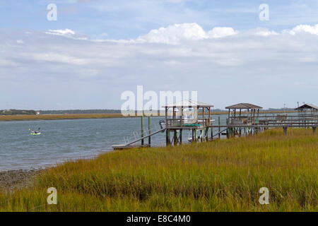 Due kayakers distanti racchetta dal molo e ed un guscio spiaggia presso la costa del South Carolina Foto Stock