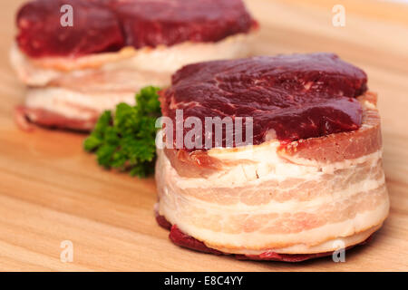 Due 8oz filet mignon bistecche di manzo avvolto con pancetta affumicata su un legno tagliere. Foto Stock