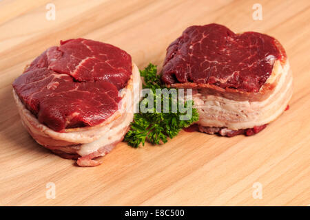 Due 8oz filet mignon bistecche di manzo avvolto con pancetta affumicata su un legno tagliere. Foto Stock