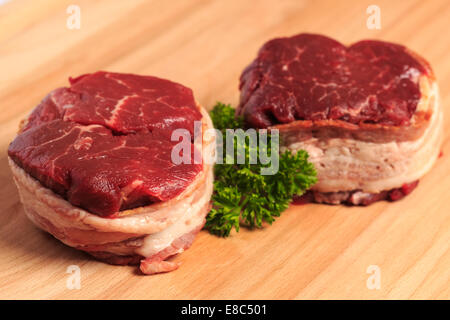 Due 8oz filet mignon bistecche di manzo avvolto con pancetta affumicata su un legno tagliere. Foto Stock