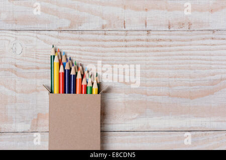 Alta angolazione di una scatola di multi-matite colorate su un bianco tavola di legno. Le matite sono parzialmente al di fuori del box set a una SID Foto Stock