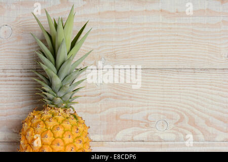 Elevato angolo di visione di un fresco prelevato ananas posa sul suo lato su un rustico di legno bianco tavola. Il frutto è dorato di colore con i Foto Stock