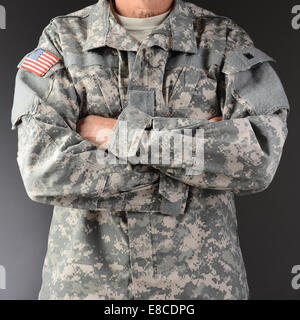 Primo piano di un soldato che indossa il camuffamento fatiche con le braccia piegate. Formato quadrato, l uomo è irriconoscibile. Foto Stock