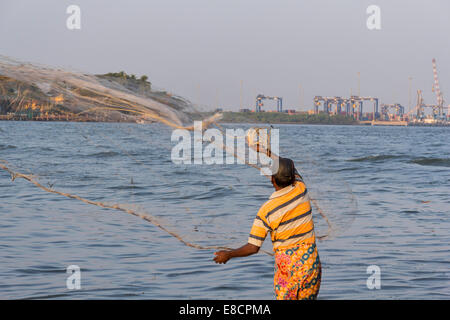 Reti CINESI A COCHIN O KOCHI INDIA con un pescatore solitario fusione il suo piccolo NET IN VIE NAVIGABILI Foto Stock