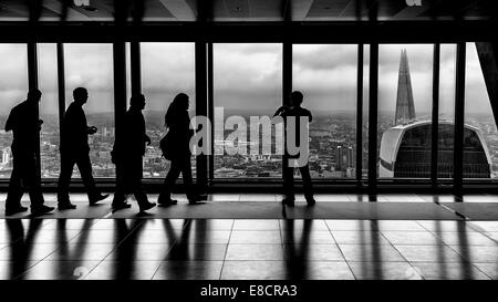 Sagome di persone che guardano da una finestra di ufficio in tutta la città di Londra, il walkie-talkie e la Shard Foto Stock