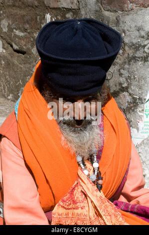 Elegante barbuto sadhu in abiti dello zafferano, argento Perline & illustri hat mediante il soleggiato fiume sacro Gange Rishikesh Uttarakanth Foto Stock