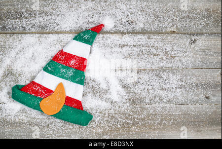 L'immagine orizzontale di Natale elf calza hat su rustiche tavole di legno ricoperta di neve Foto Stock