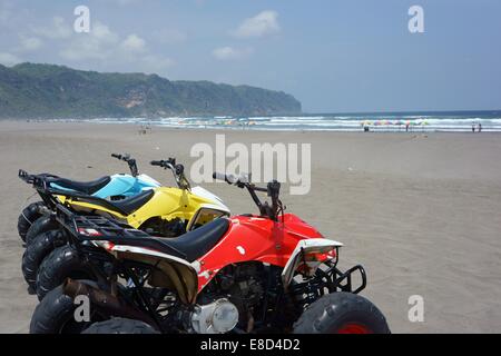 Con abbondanza di spazio per i turisti di godere in sella alla moto quad come sono in attesa in linea su una quasi deserta spiaggia indonesiano Foto Stock