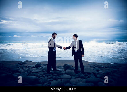 Imprenditori stringono le mani con stormy Sfondo oceano. Foto Stock