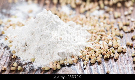 Farina di grano saraceno con alcuni grani scuri su sfondo di legno Foto Stock