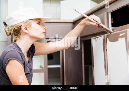 Primo piano della donna Azienda Spazzola di vernice e verniciatura di mobili da cucina Foto Stock