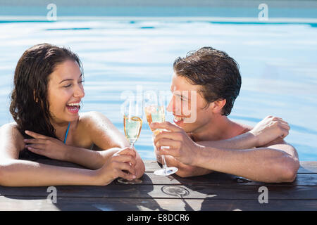 Allegro giovane tostare champagne in piscina Foto Stock