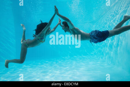 Giovane tenendo le mani e nuotare sott'acqua Foto Stock