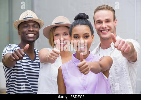 Colleghi creativi gesticolando pollice in alto Foto Stock