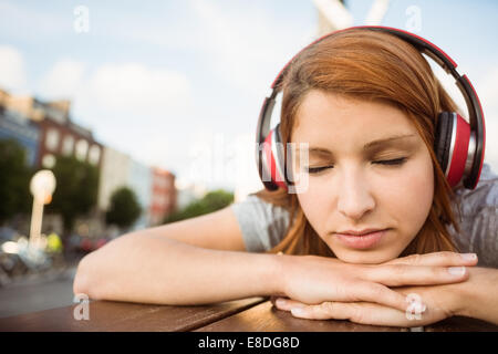 Donna l'ascolto con le cuffie per la musica con gli occhi chiusi Foto Stock