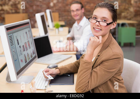 Sorridendo gli editor di foto utilizzando i computer in ufficio Foto Stock