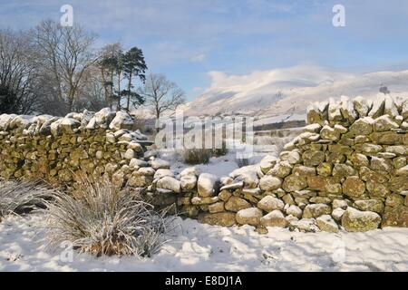 La montagna a doppio spiovente o Blencathra osservata attraverso un gap in una pietra a secco sulla parete di un giorno di inverni con la neve. Foto Stock