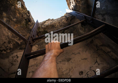 Grungy interno con la vecchia scala di metallo, cielo blu in fine e mano maschio Foto Stock