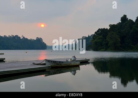 Tramonto a Singapore MacRitchie serbatoio molo sul lago con barca parcheggiata in primo piano Foto Stock