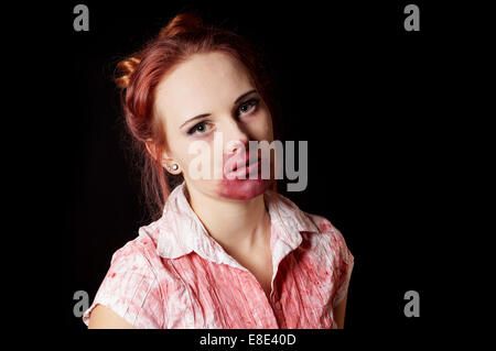 Femmina zombie con bocca sanguinante e camicetta su sfondo nero Foto Stock