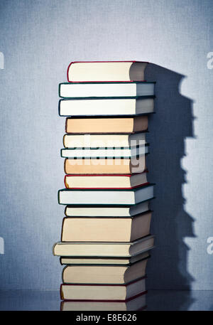 Molto alta pila di libri su un tavolo Foto Stock