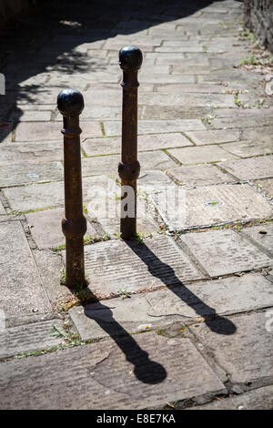 Coppia di ferro in stile vittoriano paracarri su York pavimentazione di pietra a Bristol in presenza di intensa luce solare Foto Stock