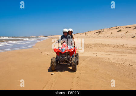 Ritratto orizzontale di un giovane uomo e donna su di una moto quad sulla spiaggia sul Marocco. Foto Stock