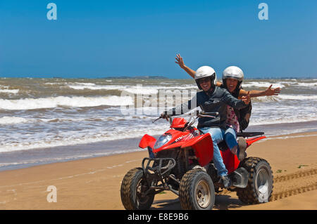 Ritratto orizzontale di un giovane uomo e donna su di una moto quad sulla spiaggia sul Marocco. Foto Stock