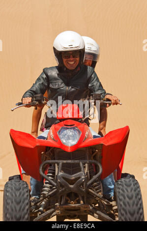 Ritratto verticale di un giovane uomo e donna su di una moto quad sulla spiaggia sul Marocco. Foto Stock