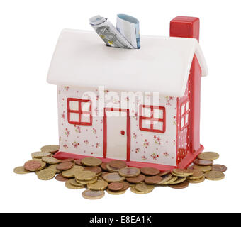 A forma di casa salvadanaio con monete e banconote in euro Foto Stock