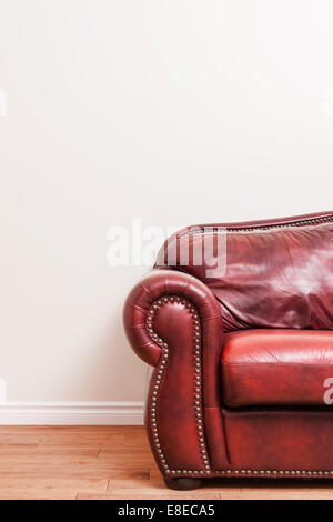 Rosso lussuoso divano in pelle dettaglio di fronte un muro grezzo a ad il vostro testo, logo, immagini, ecc. Foto Stock